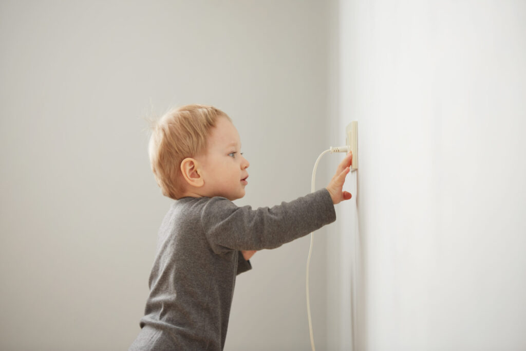 small child standing facing the wall outlet