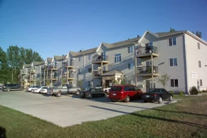 three-story apartment building with cars outside - project