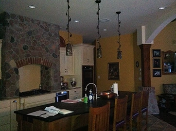 interior of a residential kitchen with hanging pendant lights and recess cans