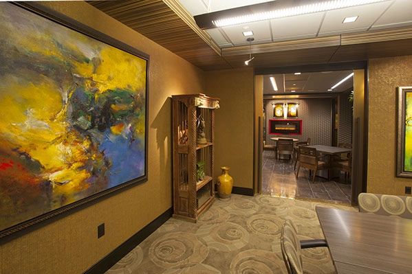 corner of an office with a painting on the wall and accent lights pointed toward the painting